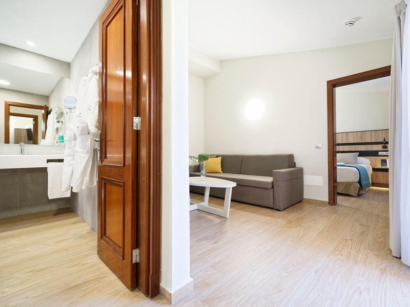 Couloir lumineux d'hôtel avec vue sur le salon et la salle de bain avec portes en bois.