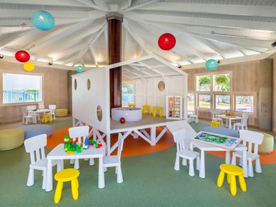 Sala giochi luminosa con tavoli, sedie colorate e giochi per bambini in hotel.