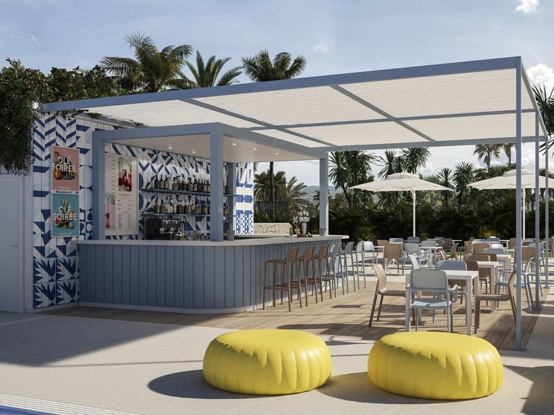 Pabellón exterior moderno con bar, mesas y cojines amarillos en un entorno tropical.
