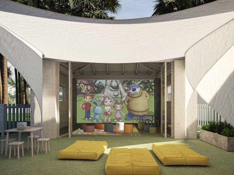 Área de juegos al aire libre moderna con toldo, cojines coloridos y arte mural en un hotel.