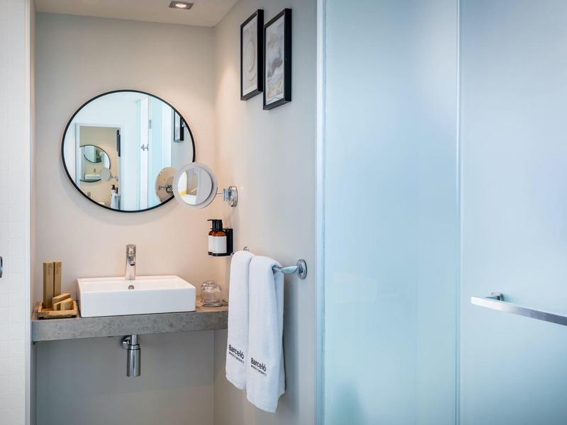 Baño moderno con espejo redondo, lavabo y toallas blancas limpias.