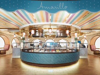 Bancone bar rotondo dell'hotel con decorazioni multicolori sul soffitto e illuminazione calda in spazio aperto.