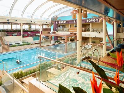 Interno di un hotel con piscina, vasca idromassaggio e grandi finestre panoramiche.