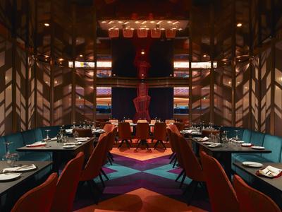 Ristorante elegante con illuminazione calda, legno scuro e arredamento moderno per una cena raffinata.