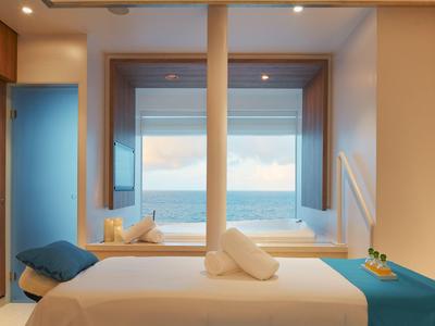 Sala massaggi luminosa con vista sul mare attraverso grandi finestre, atmosfera accogliente.