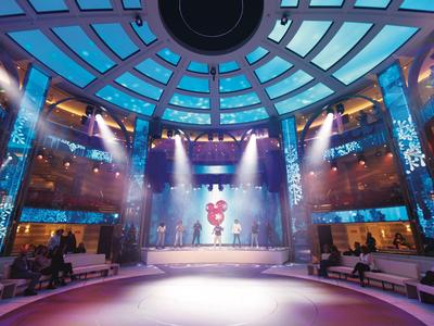 Interno moderno e circolare con tetto in vetro e fasci di luce su un palco centrale.
