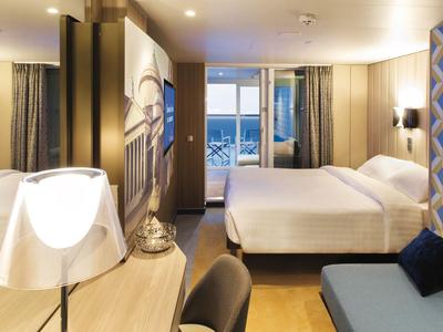 Camera d'hotel moderna con letto matrimoniale, scrivania e vista sul mare o porto.