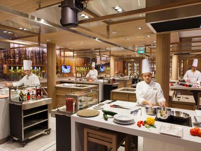 Diversi chef preparano piatti su un'isola di cucina moderna in un ristorante d'hotel.