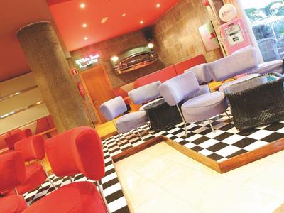 Modern hotel room with red chairs and black-and-white tiled floor.