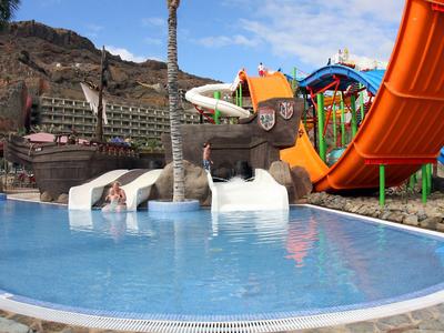 Water park with slides and pools against rocky background on a sunny day