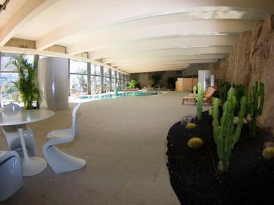 Bright modern spa area with seating and plants under a curved roof.