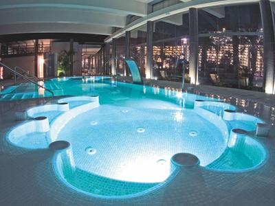 Illuminated hotel hot tub with seating areas at night.