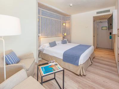 Modernes Hotelzimmer mit Doppelbett, blauen Akzenten, bequemen Stühlen und hellen Holzböden.