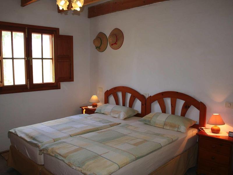 Einfaches Schlafzimmer mit zwei Einzelbetten, Holzmöbeln, Fenster und Wanddekoration aus Hüten.