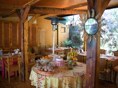 Restaurante rústico con muebles de madera y mesas decoradas bajo un área cubierta.