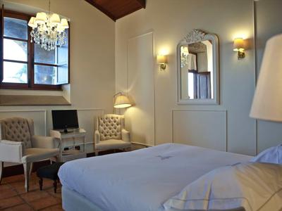 Camera d'hotel accogliente con due poltrone, scrivania e finestra grande.