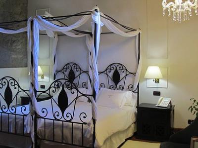 Camera accogliente con letto in metallo artistico, comodino e lampadario.