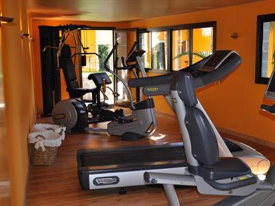 Interno di una palestra con tapis roulant, cyclette e specchi alle pareti.
