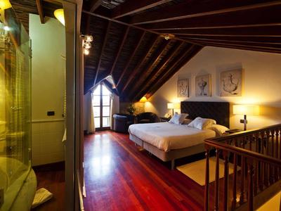 Camera d'albergo accogliente con pavimento in legno e soffitto alto inclinato