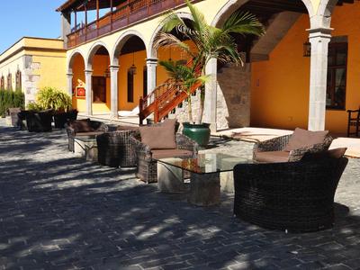 Espace extérieur d'hôtel avec fauteuils en osier et tables sous des arcades par une journée ensoleillée