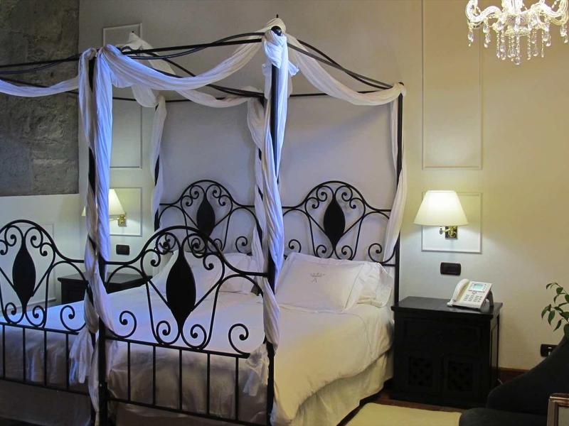 Camera accogliente con letto in metallo artistico, comodino e lampadario.