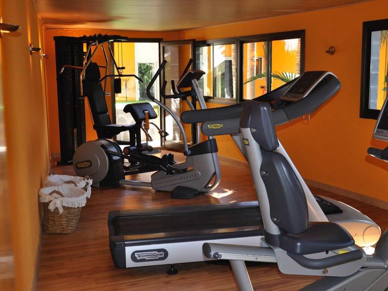 Interno di una palestra con tapis roulant, cyclette e specchi alle pareti.