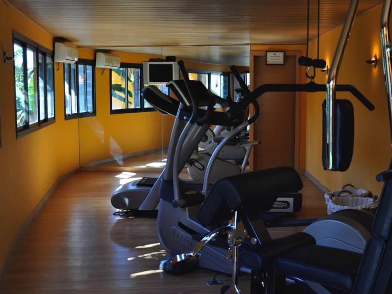 Piccola palestra con varie attrezzature da allenamento e pareti gialle.