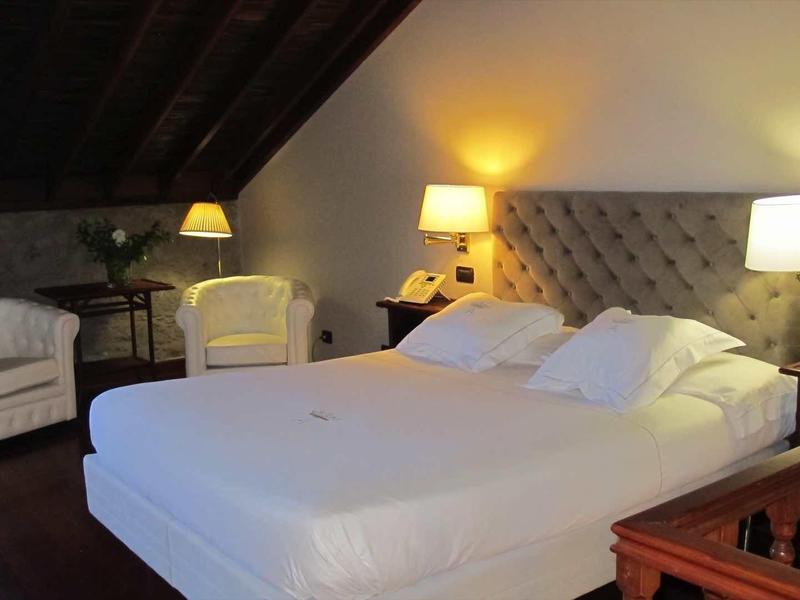 Camera accogliente con letto grande, poltrone e illuminazione sotto soffitto inclinato.