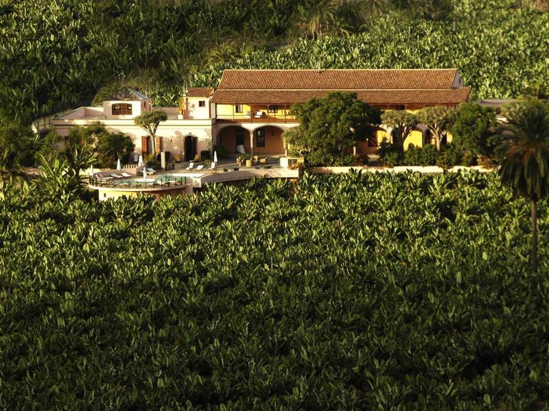 Casa con terrazze e piscina, circondata da una vegetazione fitta.