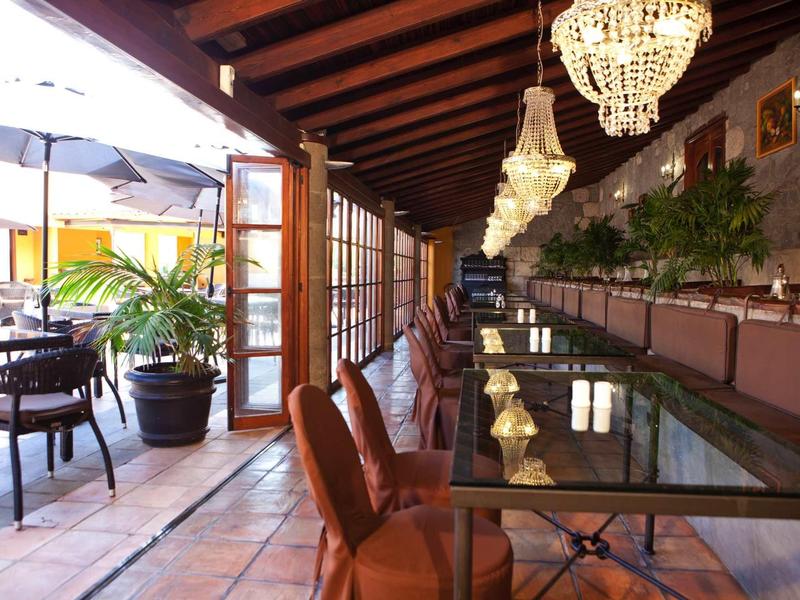 Ristorante elegante con tavoli in vetro e lampadari in ambiente tropicale.