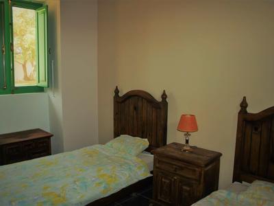 Chambre double avec mobilier en bois, fenêtre ouverte et lampe orange.