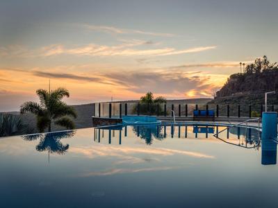 Piscina a sfioro con palme e vista sulle montagne al tramonto