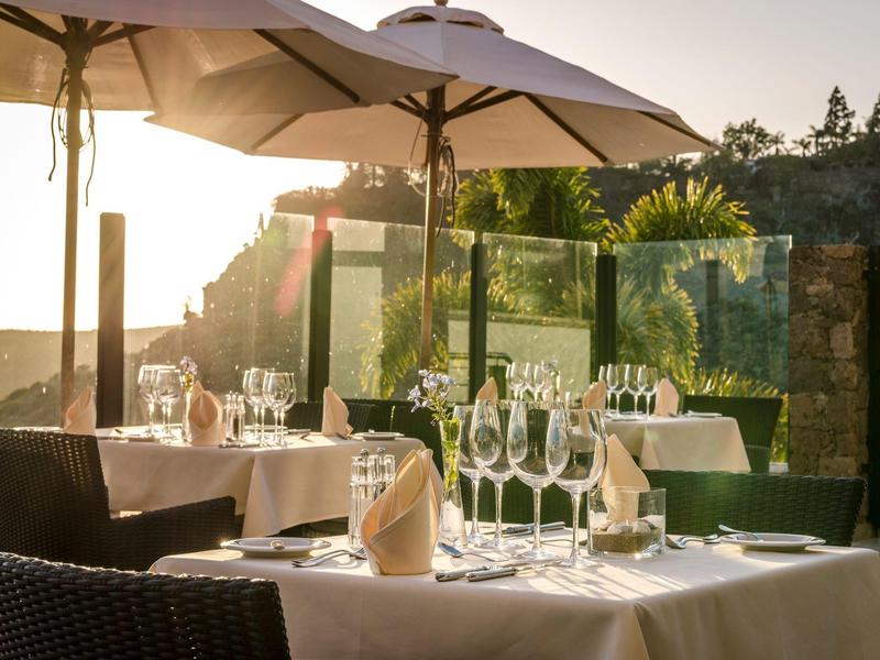Ristorante elegante all'aperto con tavoli apparecchiati e ombrelloni al tramonto.