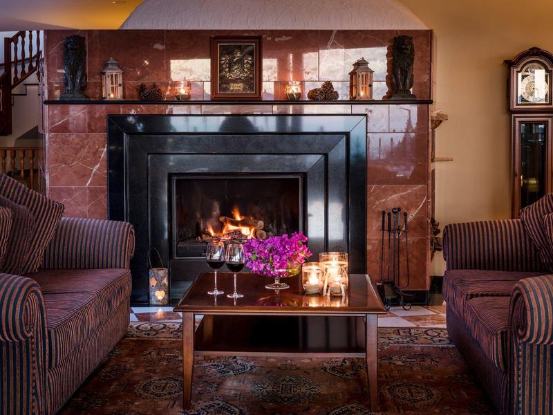 Zona giorno accogliente con camino, due poltrone, tavolo e luce calda.