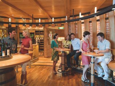 Des personnes se détendent dans un bar élégant avec un intérieur en bois et des casiers à vin.