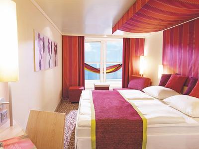 Chambre avec lit double, rideaux rouges et vue sur une terrasse avec hamac.