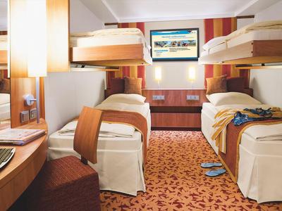 Hotel room with four bunk beds, carpeted floor, and bright lamp lighting.