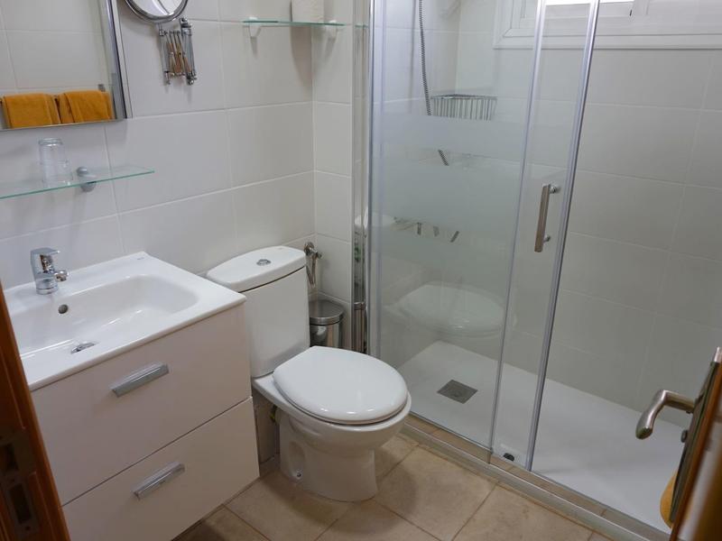 Petite salle de bains avec lavabo, toilette et cabine de douche avec portes en verre.