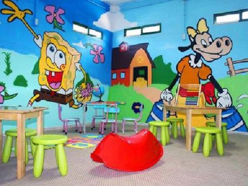 Bunter Kinderraum mit grünen und blauen Wänden, SpongeBob- und Kuh-Figuren, bunten Hockern und Spielzeug.