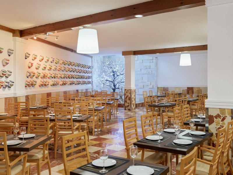 Leeres Restaurant mit vielen Holztischen und -stühlen, gedeckt mit Tellern und Gläsern.