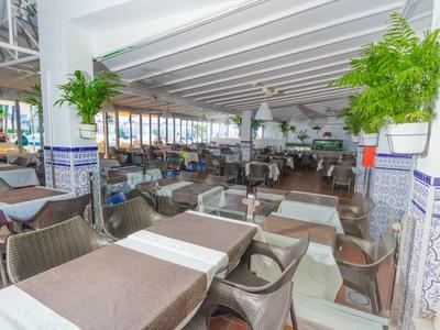 Světla, otevřená restaurace s prostřenými stoly a výhledem na moře.