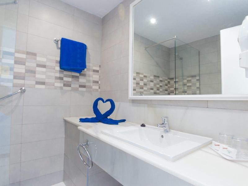 Weißes Badezimmer mit großem Spiegel, Waschbecken und blauen Handtüchern.