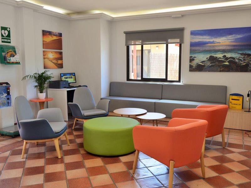 Světlá lounge s barevnými křesly, pohovkami a velkým oknem, ideální pro odpočinek.