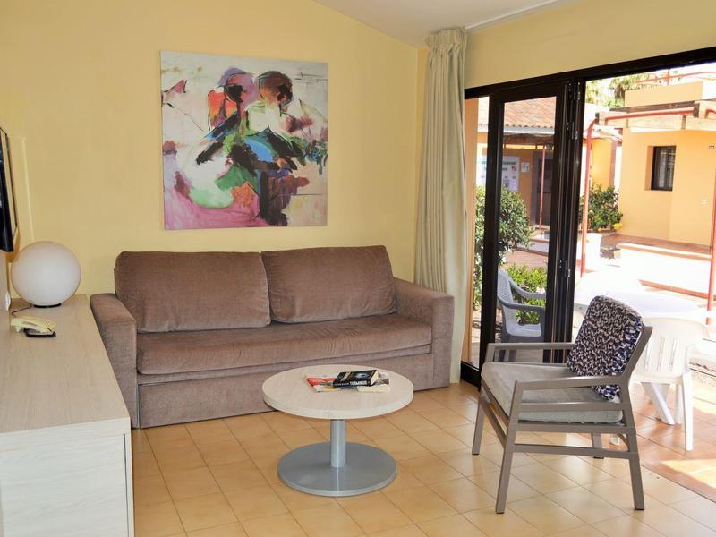 Pohodlný obývací prostor s pohovkou, křeslem a výhledem na terasu hotelu