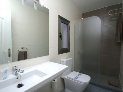 Moderní koupelna s umyvadlem, toaletou, sprchovým koutem a osvětleným zrcadlem.