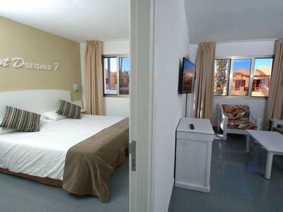 Hotelový pokoj se dvěma částmi, jedna s dvojlůžkem a druhá s pohovkou a TV