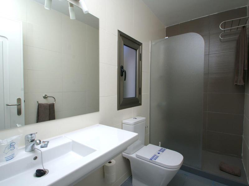 Moderní koupelna s umyvadlem, toaletou, sprchovým koutem a osvětleným zrcadlem.