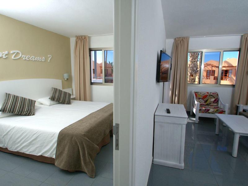 Hotelový pokoj se dvěma částmi, jedna s dvojlůžkem a druhá s pohovkou a TV