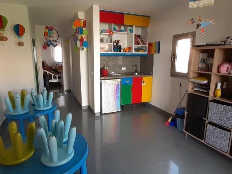 Barevná, dobře uspořádaná dětská místnost s regály, židlemi a nástěnnými dekoracemi pro dovolenkové hosty.