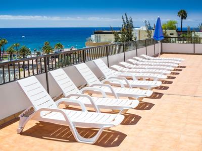 Reihe leerer weißer Sonnenliegen auf Terrasse mit Blick aufs Meer.